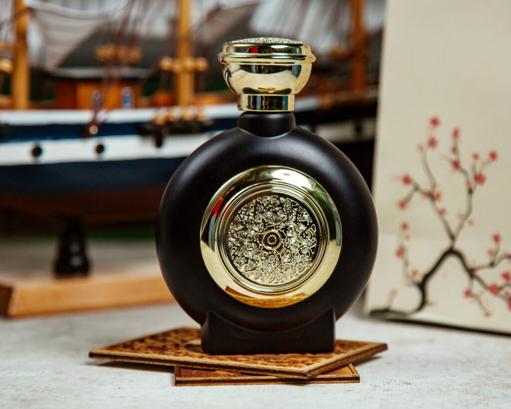 A bottle of perfume elegantly placed on a table beside a small boat, creating a serene and stylish atmosphere.