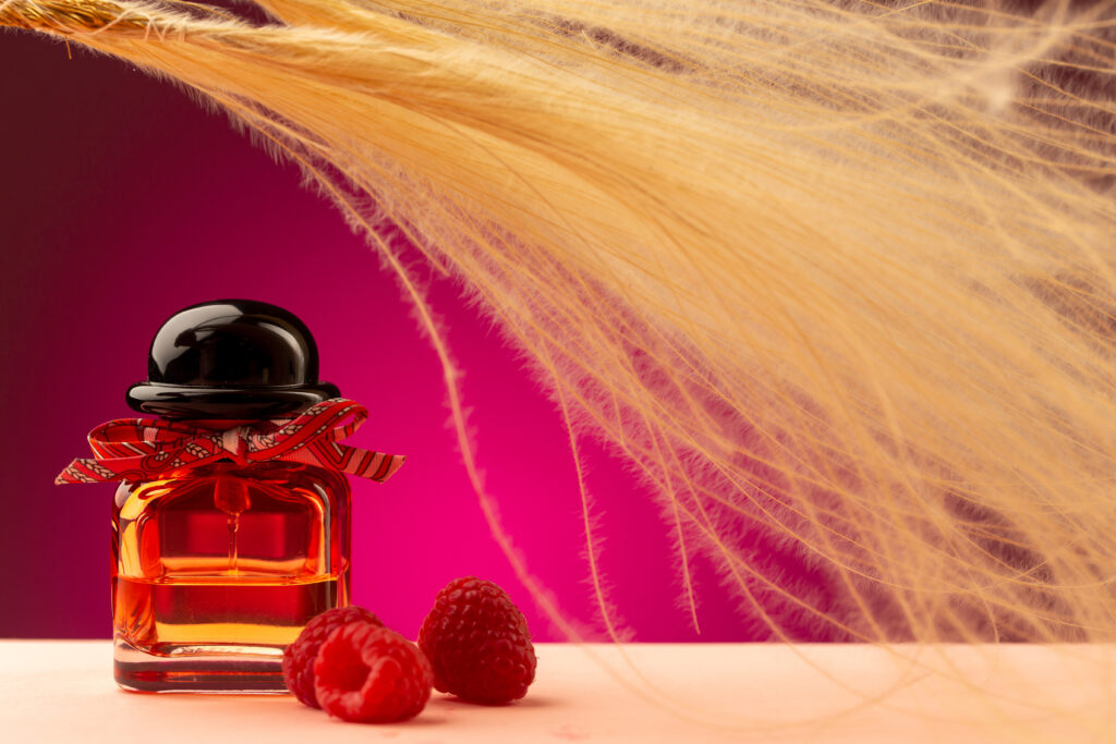 A bottle of perfume beside fresh raspberries on a wooden table, showcasing a blend of elegance and natural beauty.